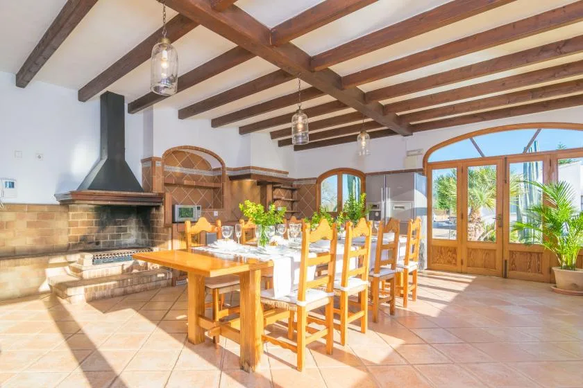 Comedor con una larga mesa de madera bajo vigas de techo vistas.