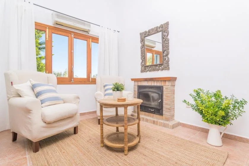 Una sala luminosa con chimenea, asientos y una mesa redonda de madera.