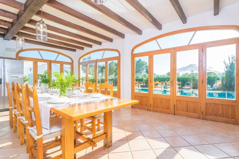 Un comedor luminoso con una mesa larga de madera junto a grandes puertas de vidrio.