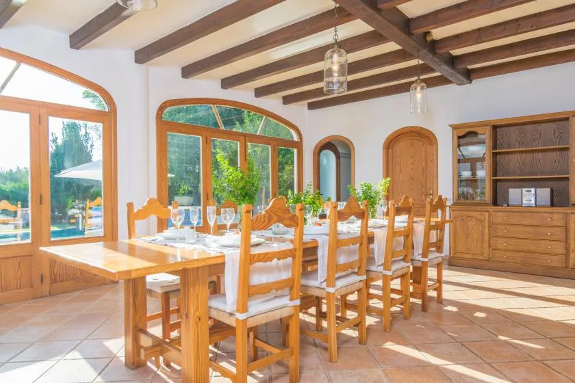 Un comedor luminoso con una mesa larga de madera y grandes ventanas.