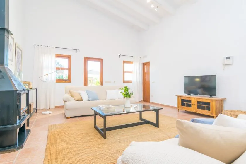 Una sala de estar luminosa con asientos alrededor de una mesa de centro y un televisor.