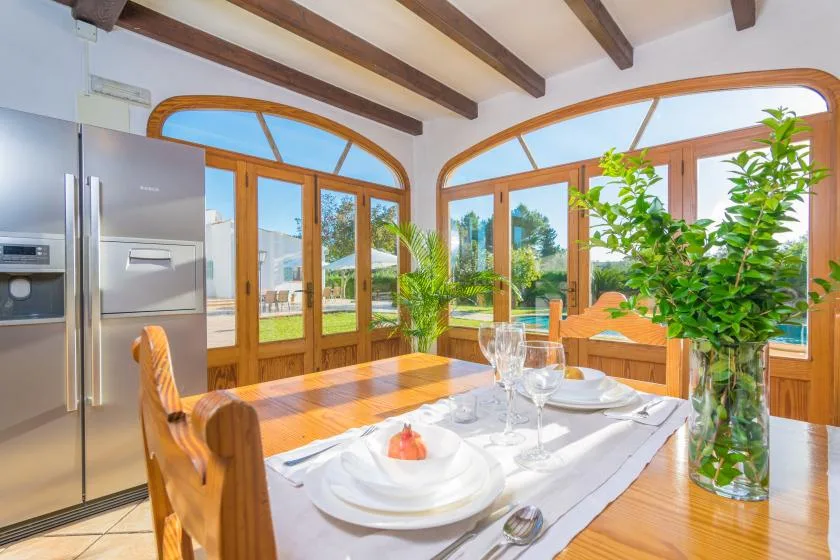 Comedor con una mesa de madera puesta junto a grandes ventanales arqueados.