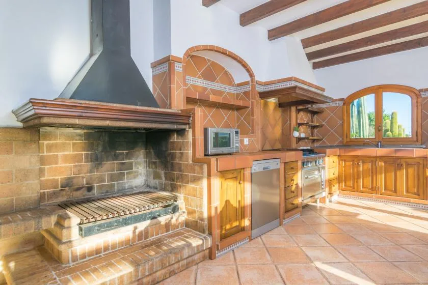 Una cocina rústica con chimenea de ladrillo, encimeras de azulejos y gabinetes de madera.