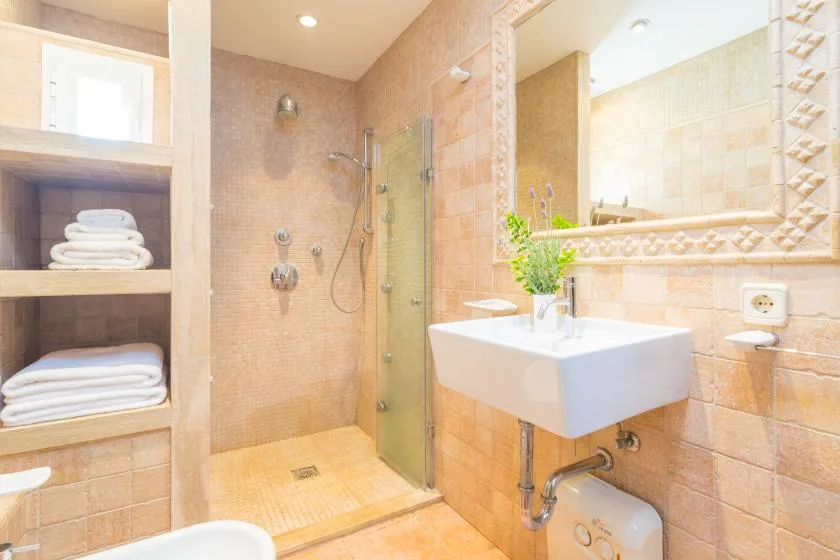 Un baño alicatado con ducha y lavabo suspendido.