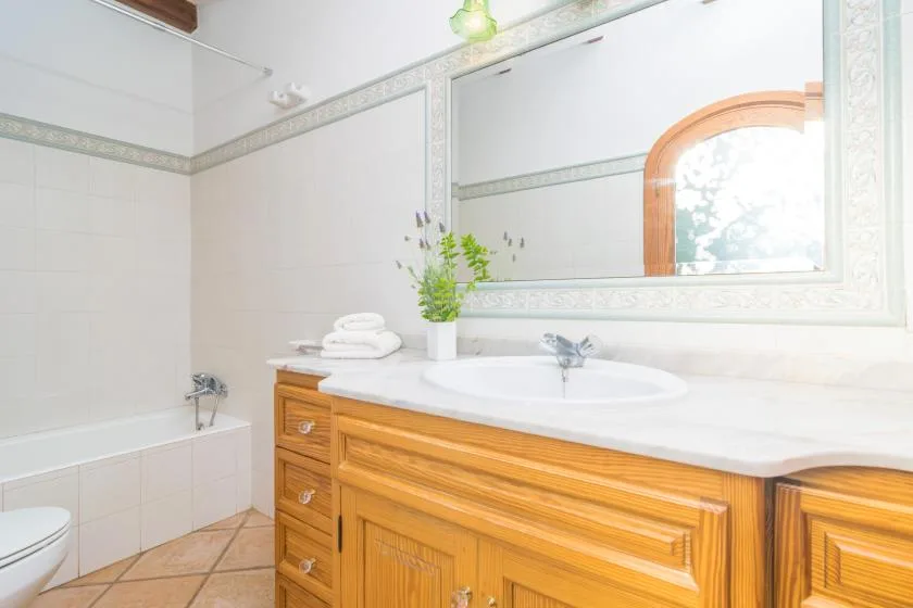 Un baño luminoso tiene una bañera junto a un tocador de madera con lavabo.