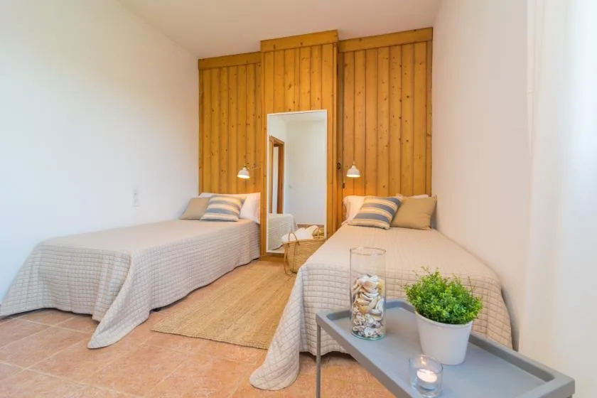 Un dormitorio con dos camas y un panel de madera detrás.