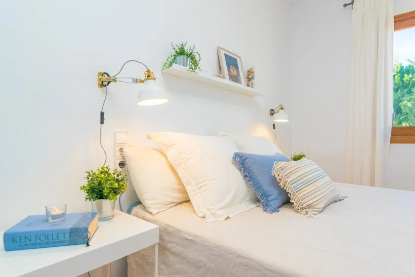 Un dormitorio con una cama, varias almohadas y luces junto a la cama.