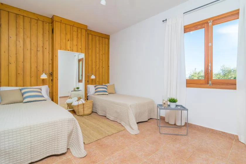 Un dormitorio con dos camas, una pared de madera y una ventana.
