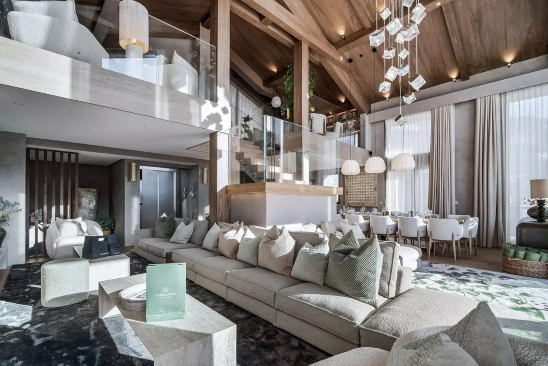 Una amplia sala de estar con asientos, una mesa de comedor y ventanas altas con cortinas.