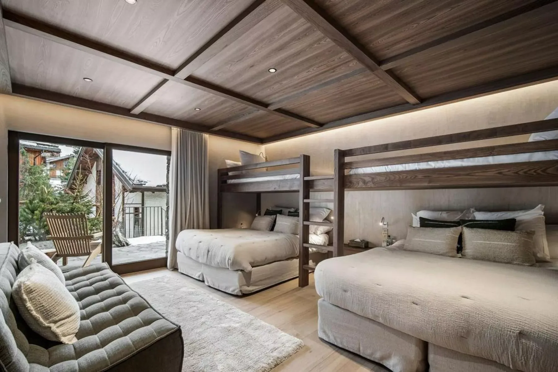 Un dormitorio con dos camas, una zona de estar y puertas corredizas de vidrio.