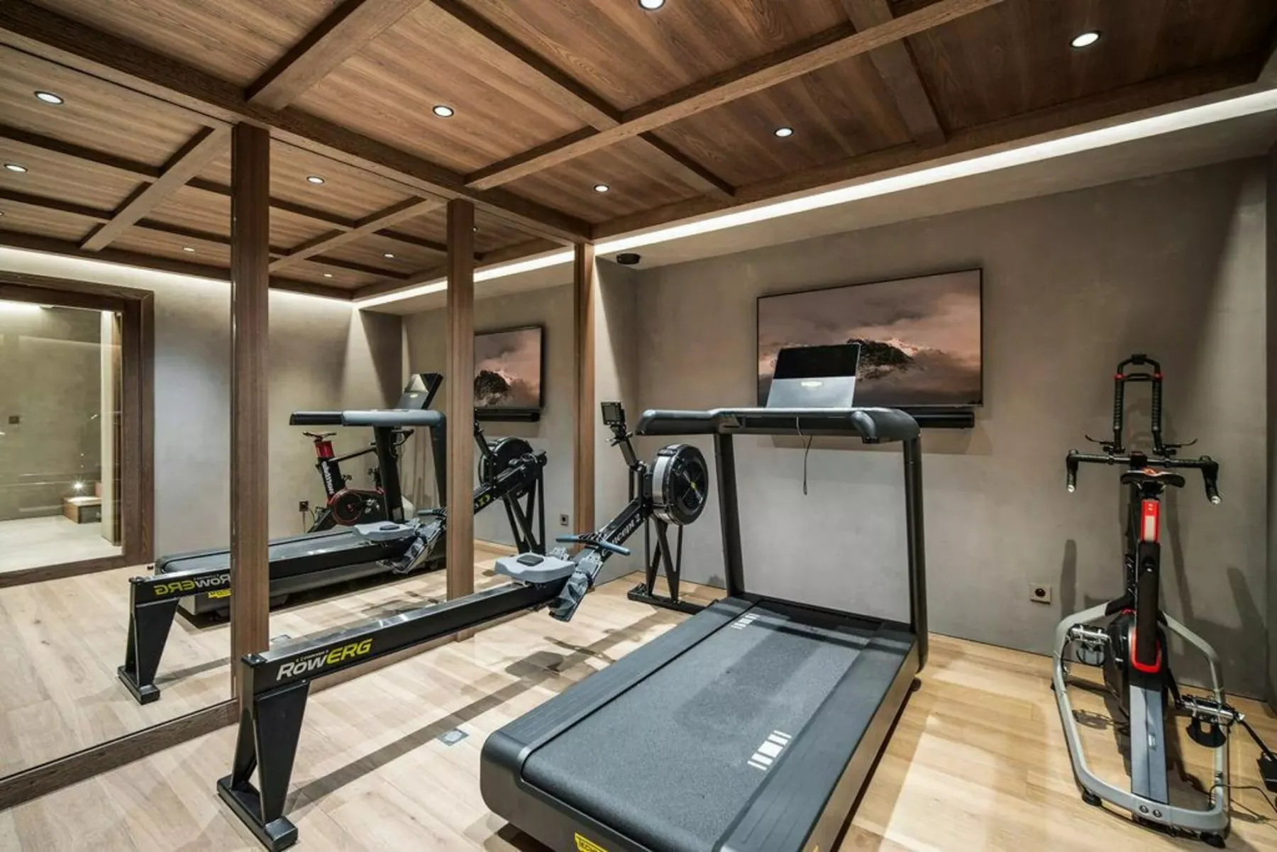 Un gimnasio con máquinas de ejercicio bajo un techo revestido de madera.