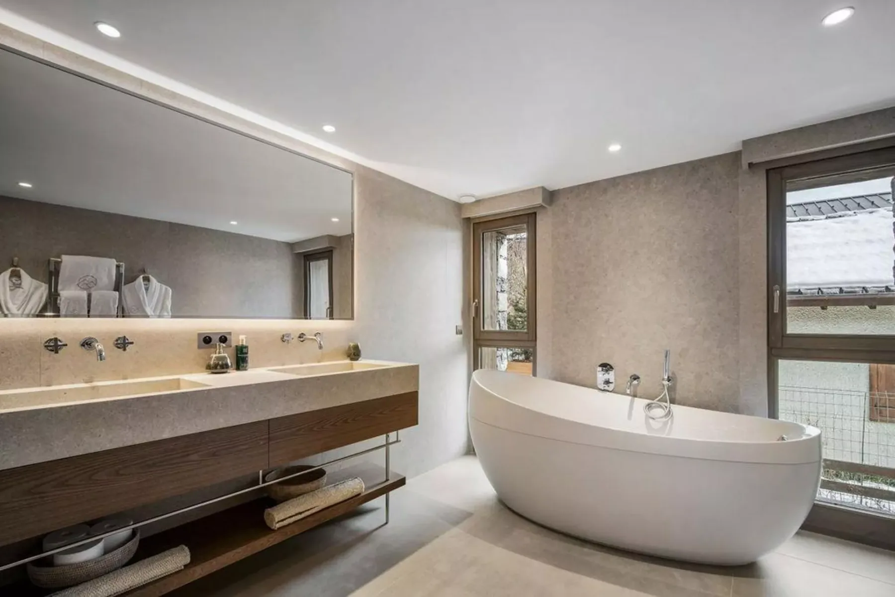 Un baño moderno con una bañera exenta y un lavabo alargado.
