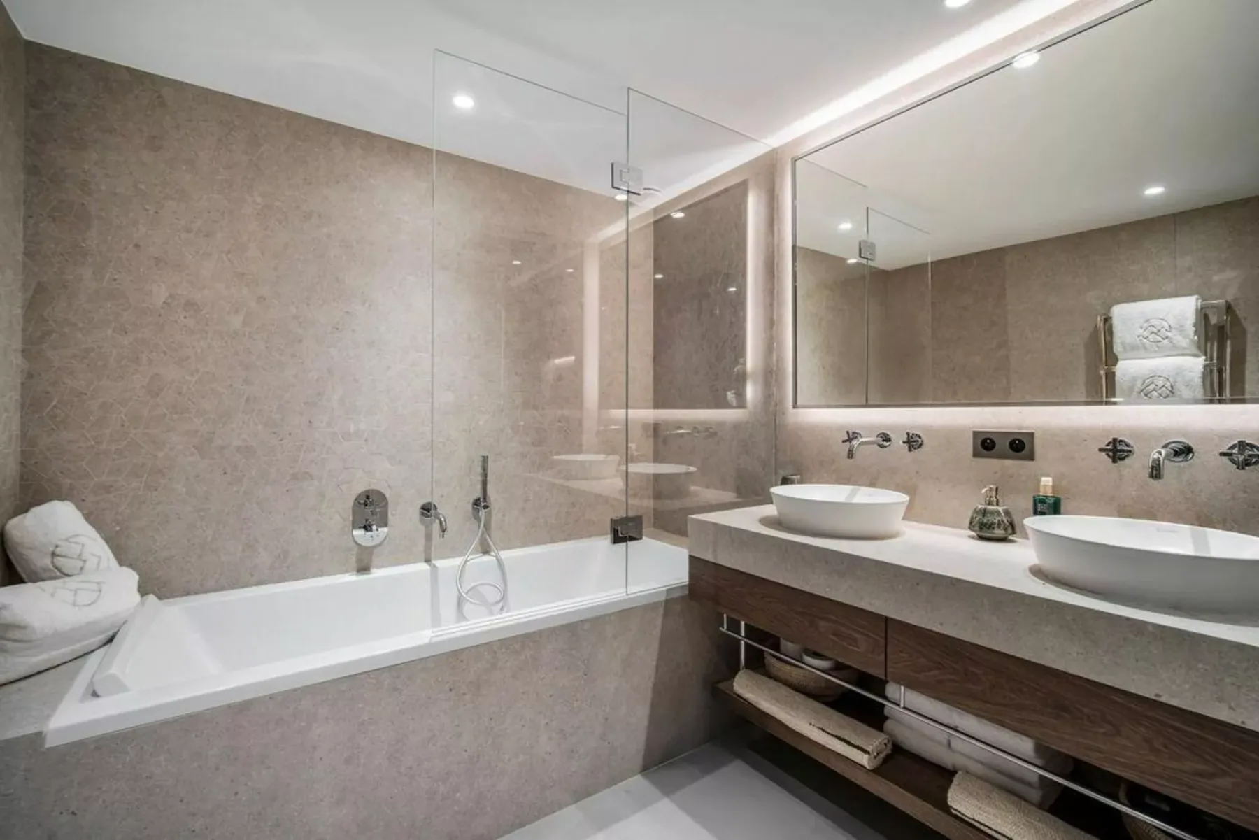 Un baño moderno con bañera y un amplio tocador con dos lavabos.