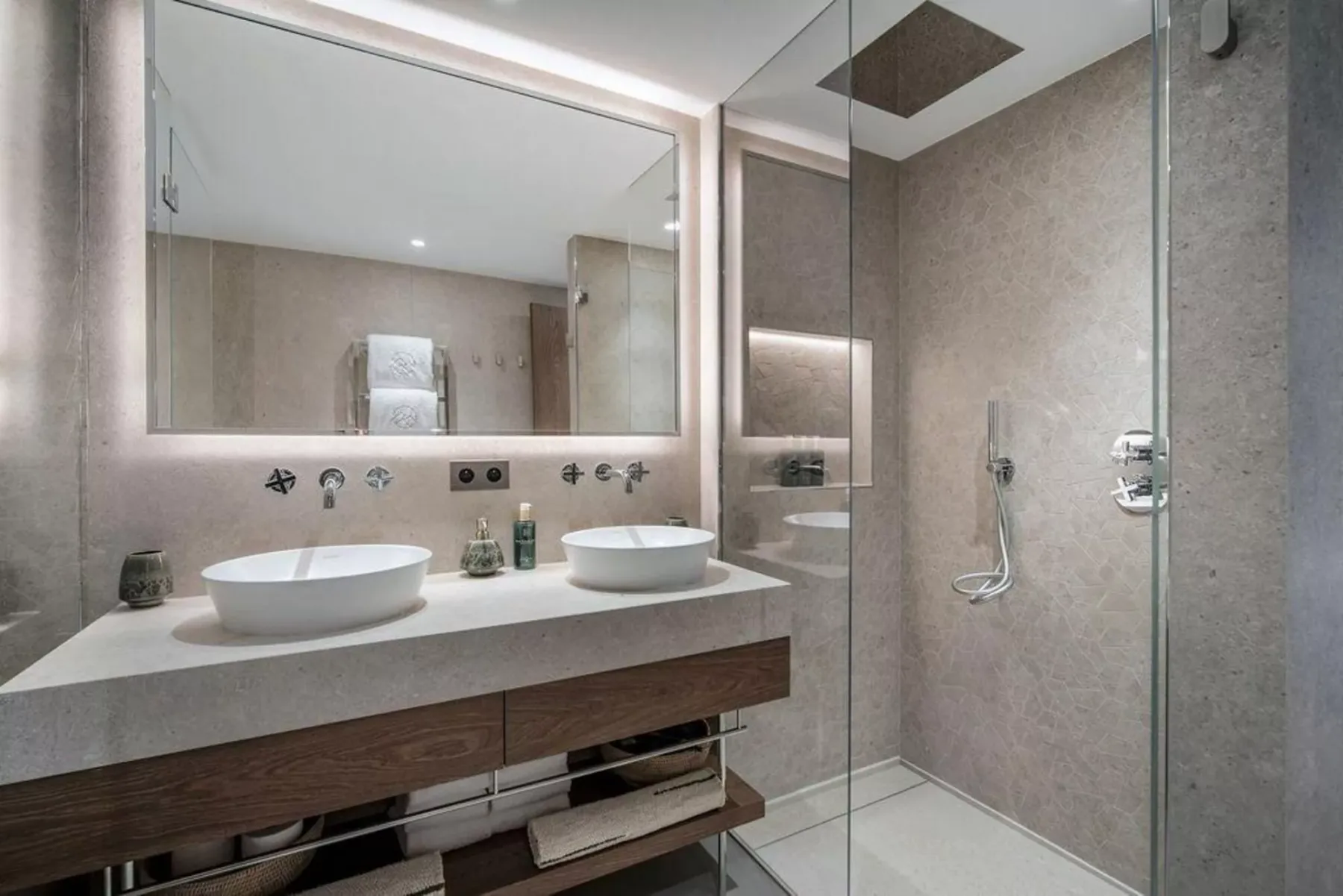 Un tocador de baño moderno con dos lavabos junto a una ducha con mampara de vidrio.