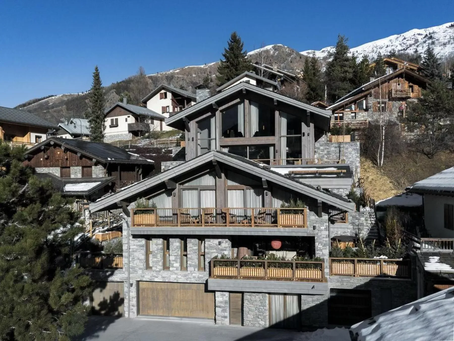 Un gran chalet de montaña con balcones se alza entre laderas alpinas nevadas.