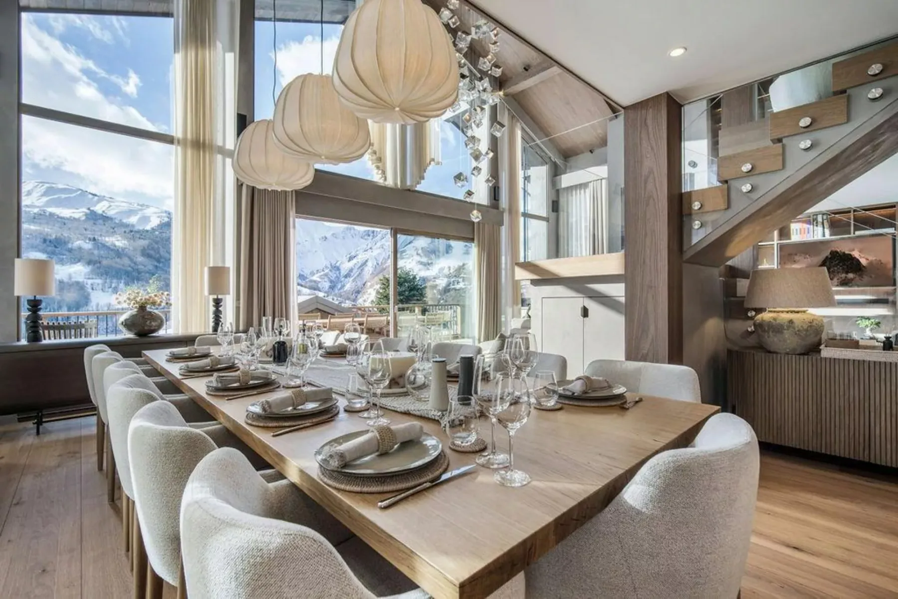 Comedor con una mesa larga y grandes ventanales con vistas a un paisaje montañoso.
