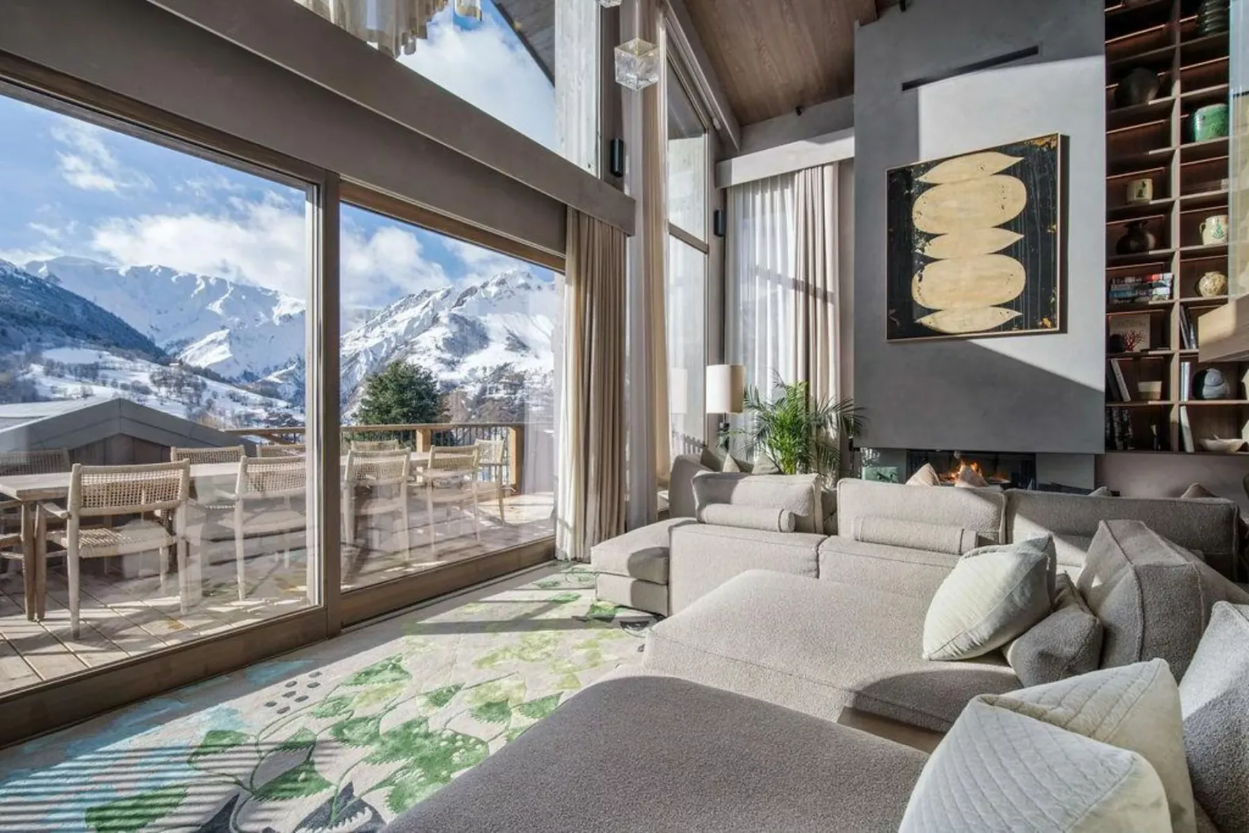 Una sala luminosa con asientos junto a grandes ventanales con vistas a montañas nevadas.