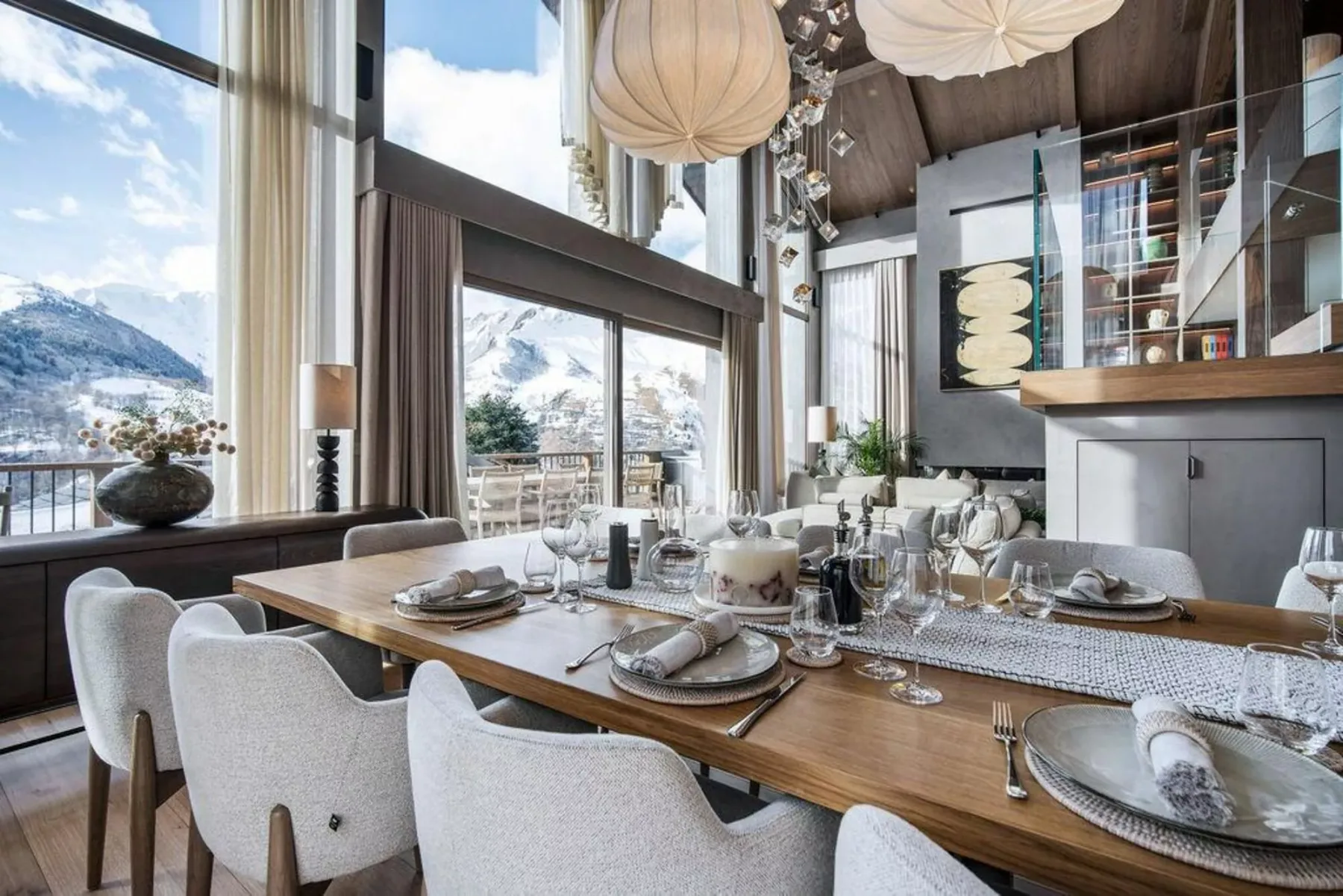 Un comedor con una mesa larga, grandes ventanales y vistas a las montañas.
