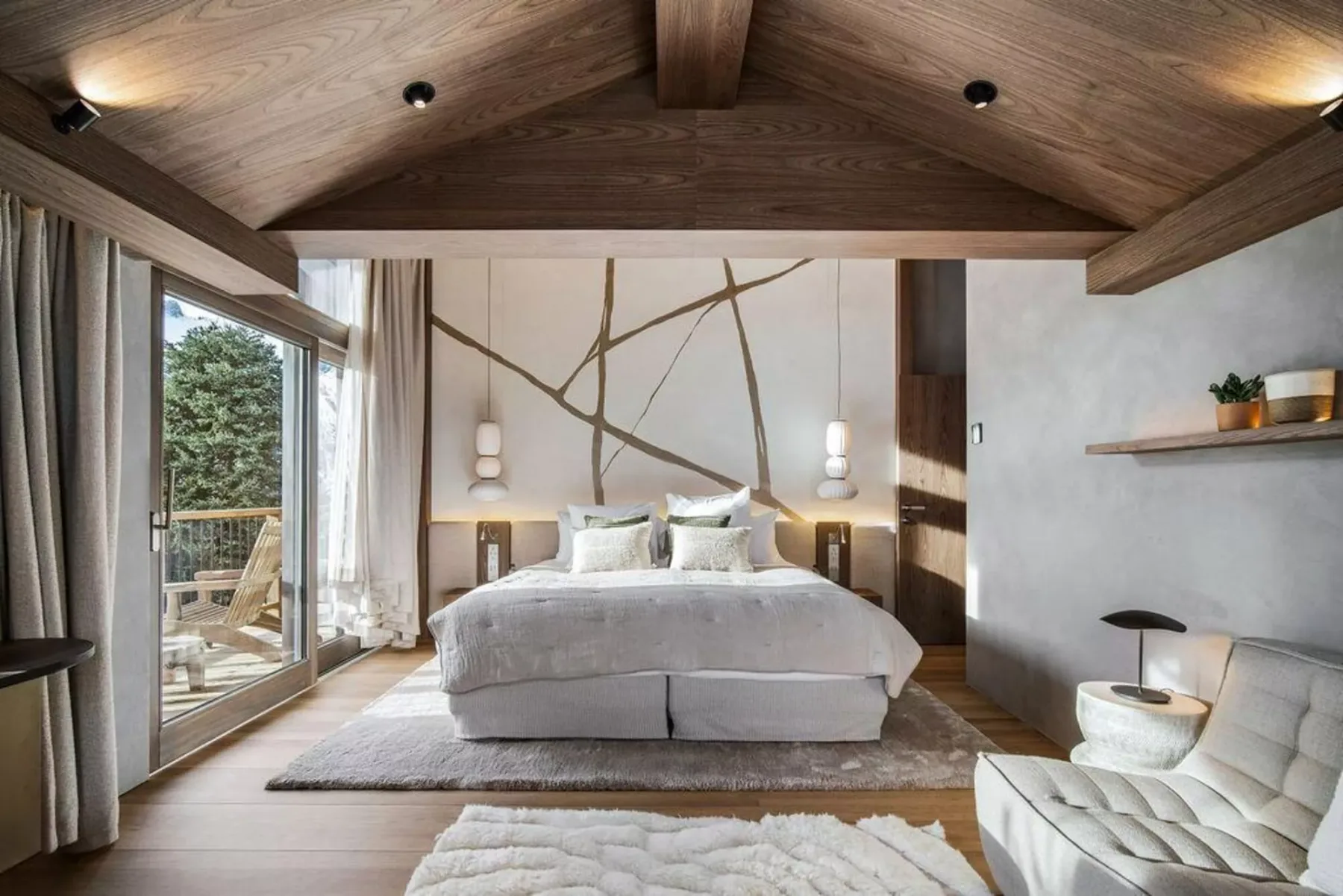 Un dormitorio con una cama bajo un techo revestido de madera y grandes puertas de vidrio.
