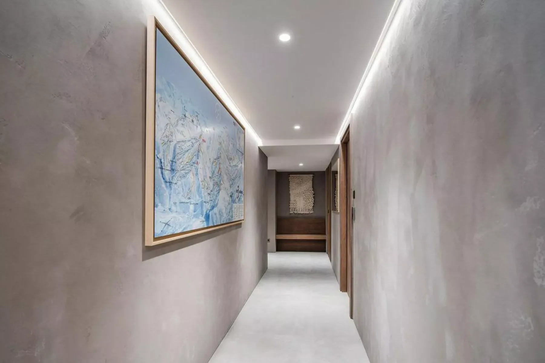 Un pasillo estrecho con una obra enmarcada en la pared y luces empotradas en el techo.