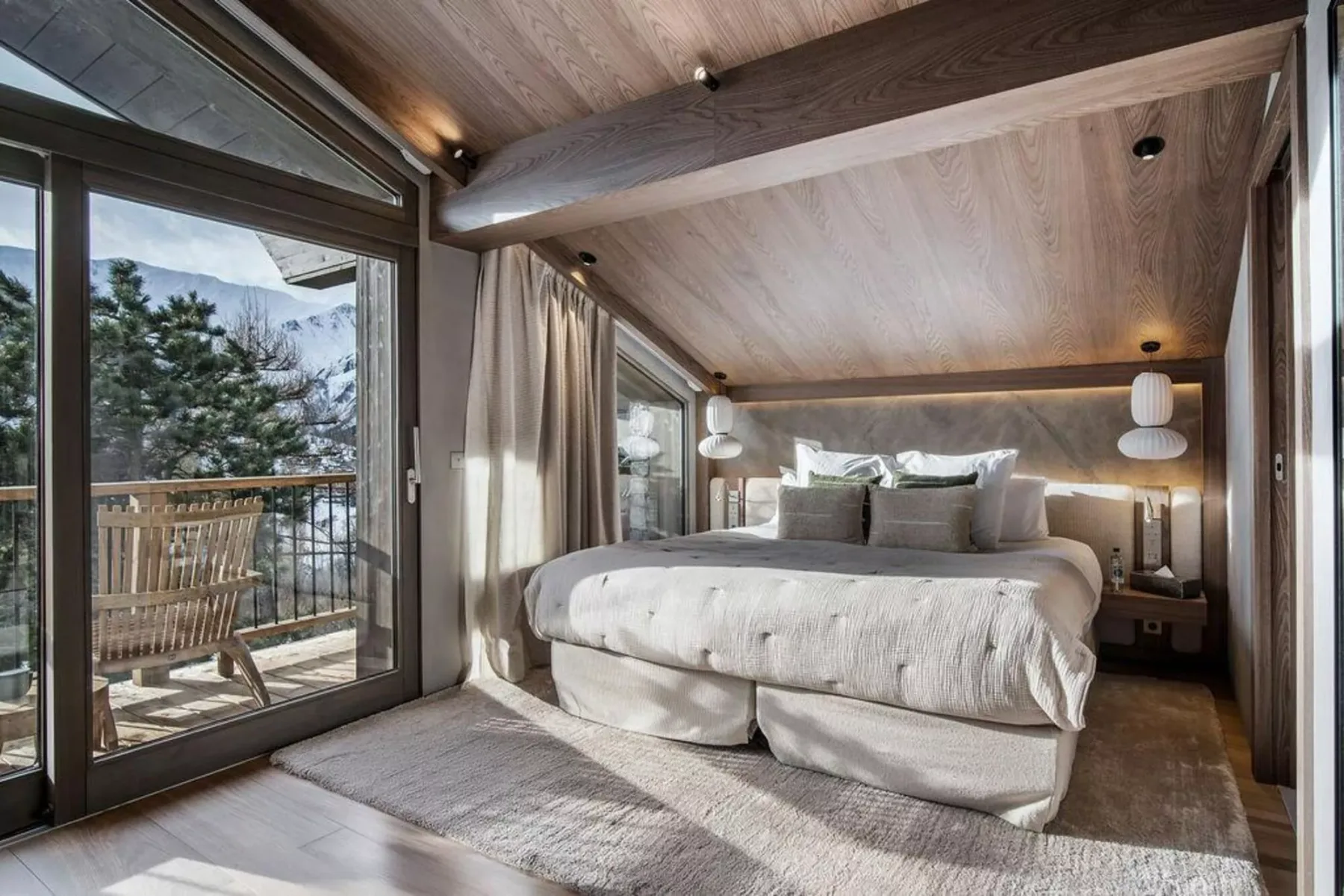 Un dormitorio con una cama grande junto a puertas de vidrio que dan a un balcón.