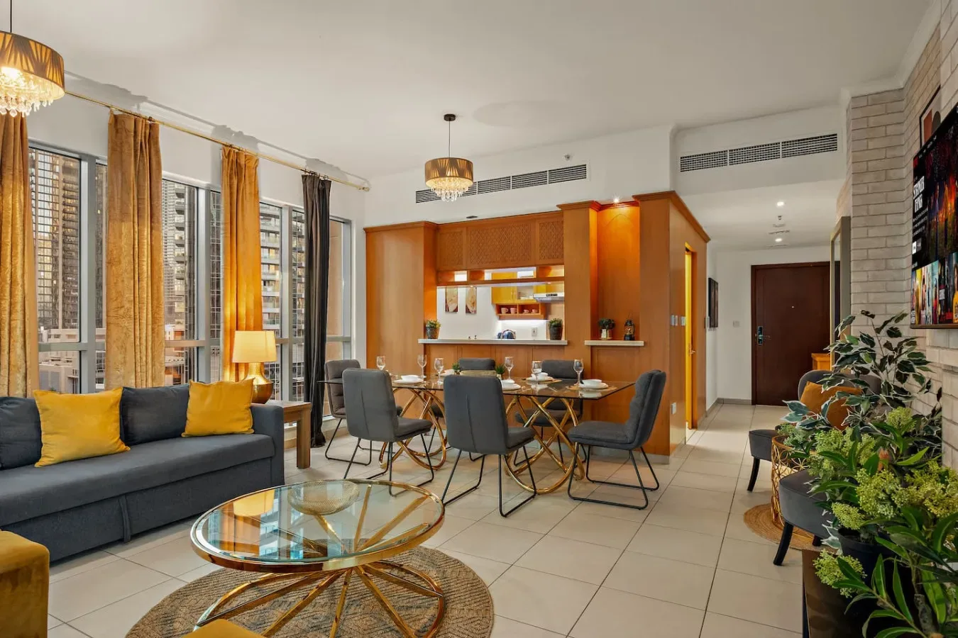 Sala de estar y comedor con asientos, una mesa de centro de vidrio y cocina abierta.