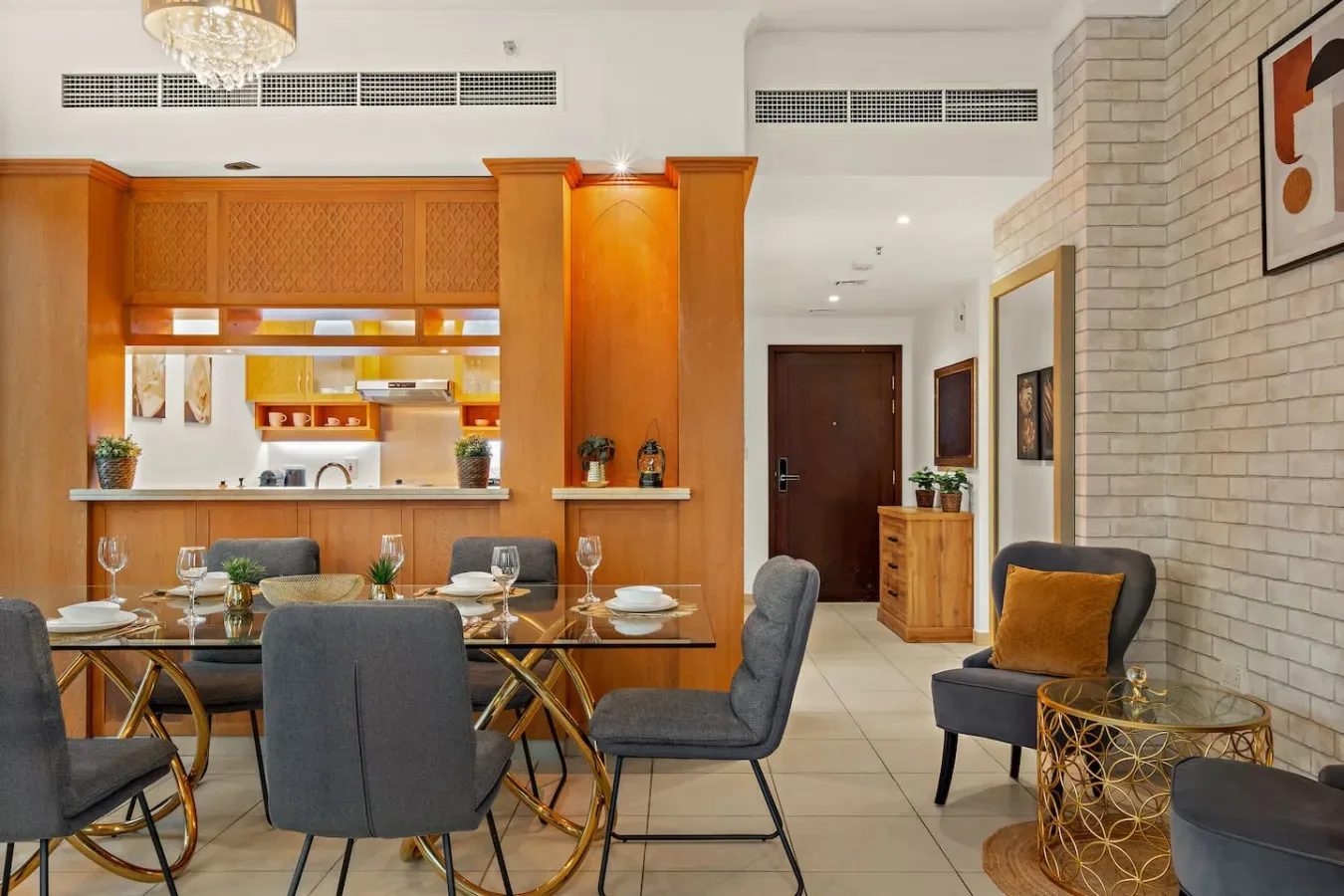Comedor con mesa de vidrio y asientos tapizados junto a una cocina abierta.