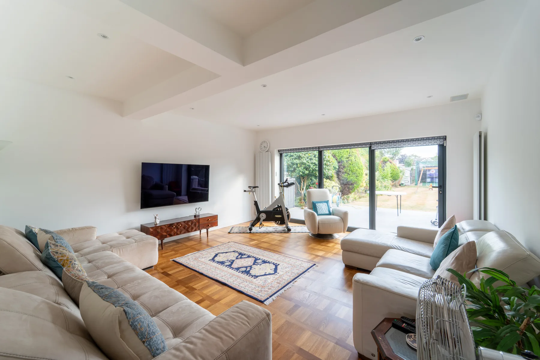 A bright living room with seating, a television, and large glass doors.