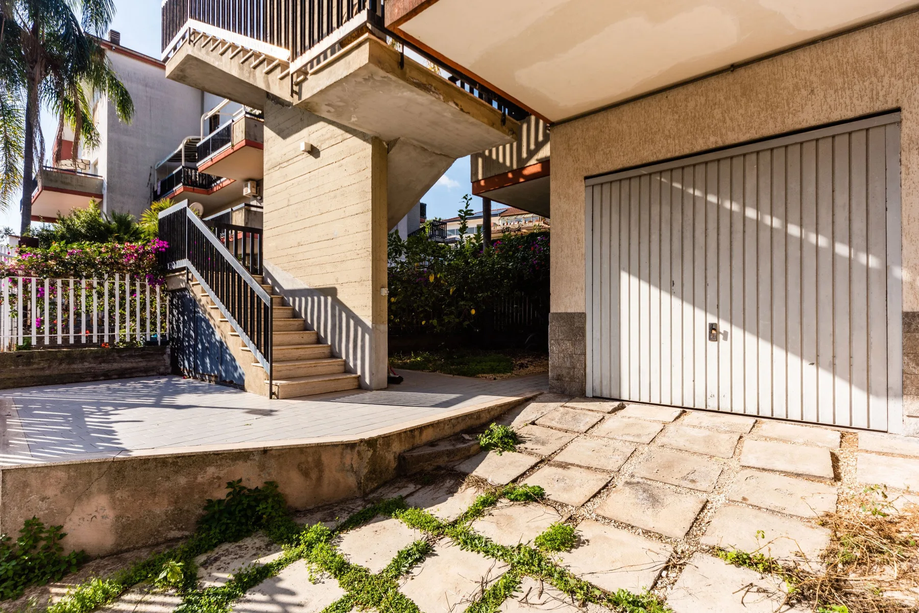 Una entrada exterior con escaleras y una puerta de garaje grande.