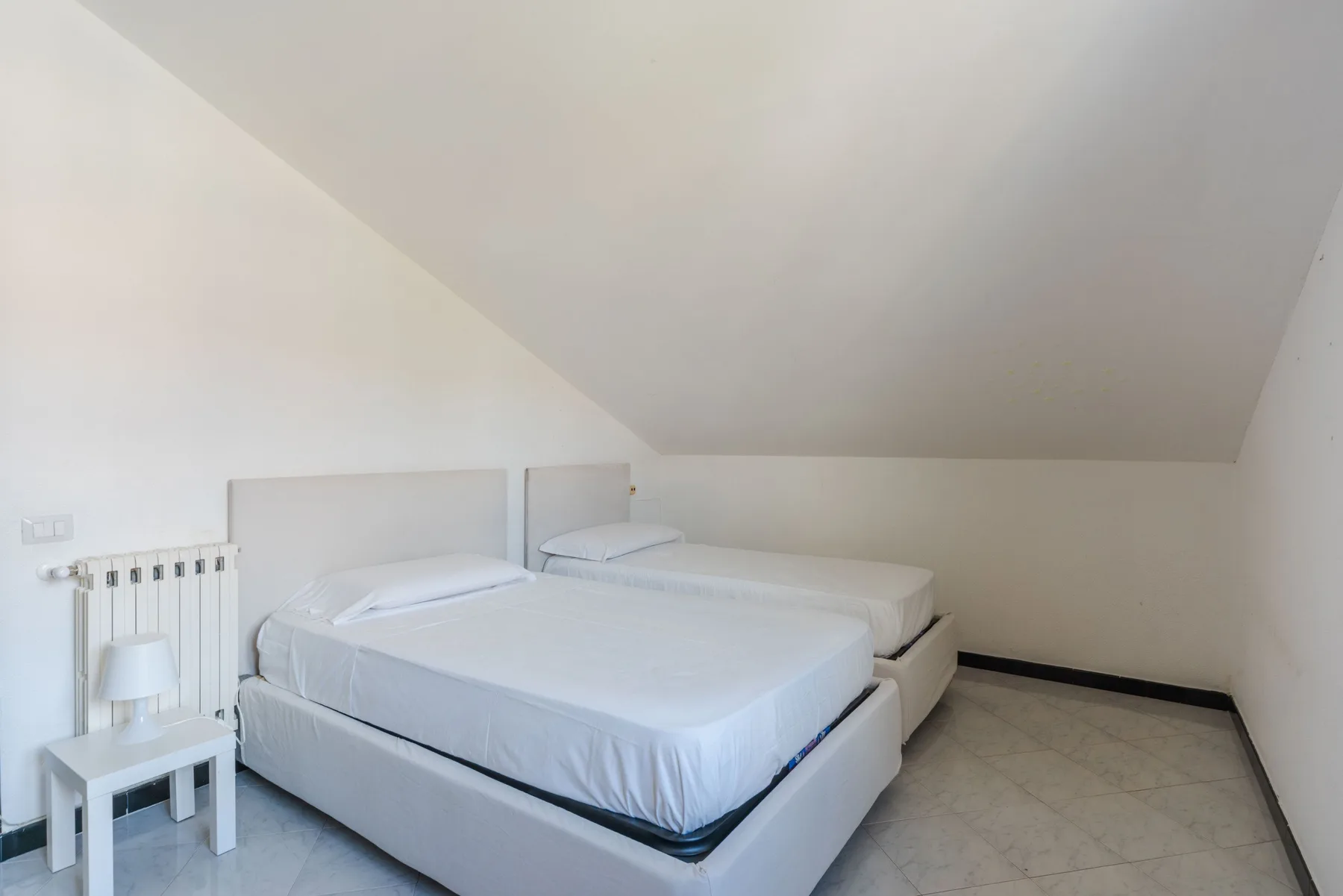 Un dormitorio con dos camas bajo un techo inclinado.