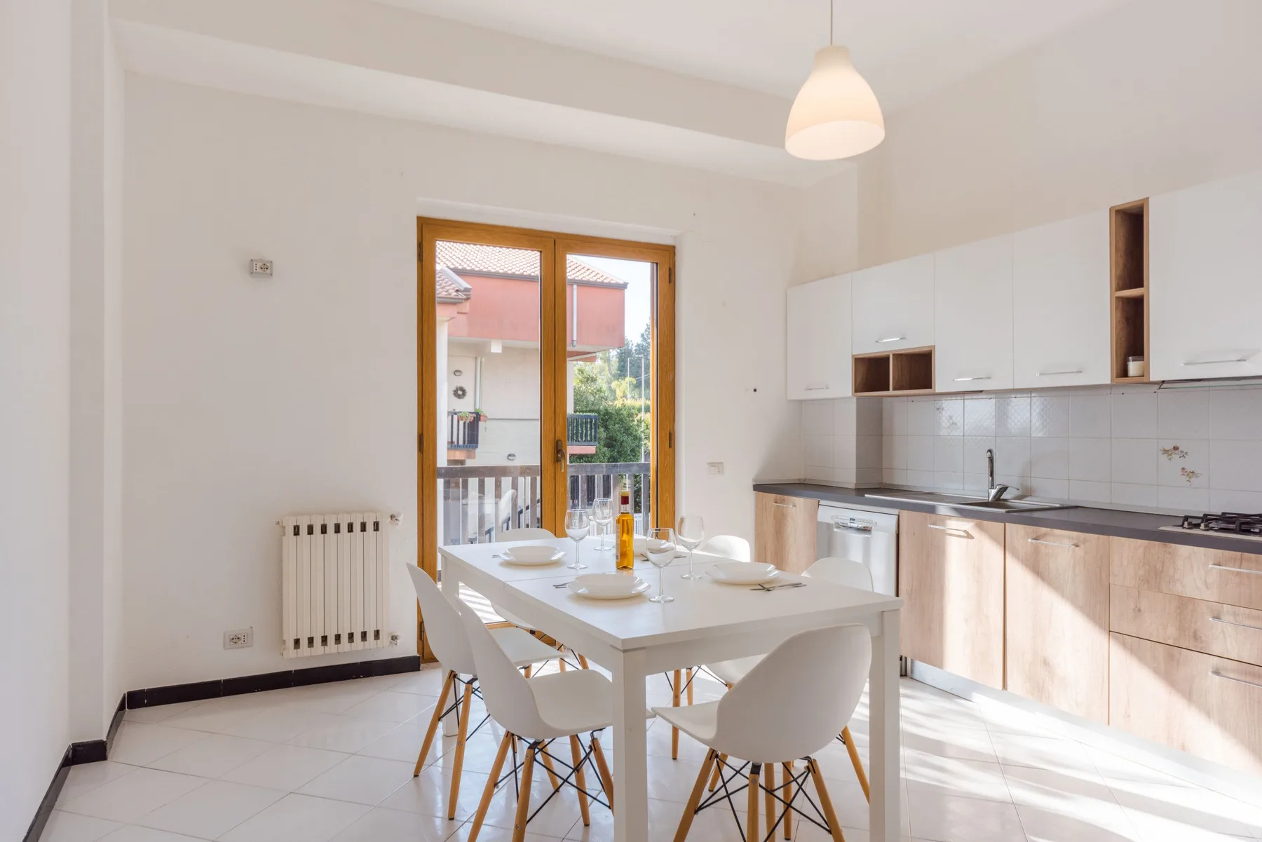 A bright dining area beside a kitchen, with a table by the glass doors.