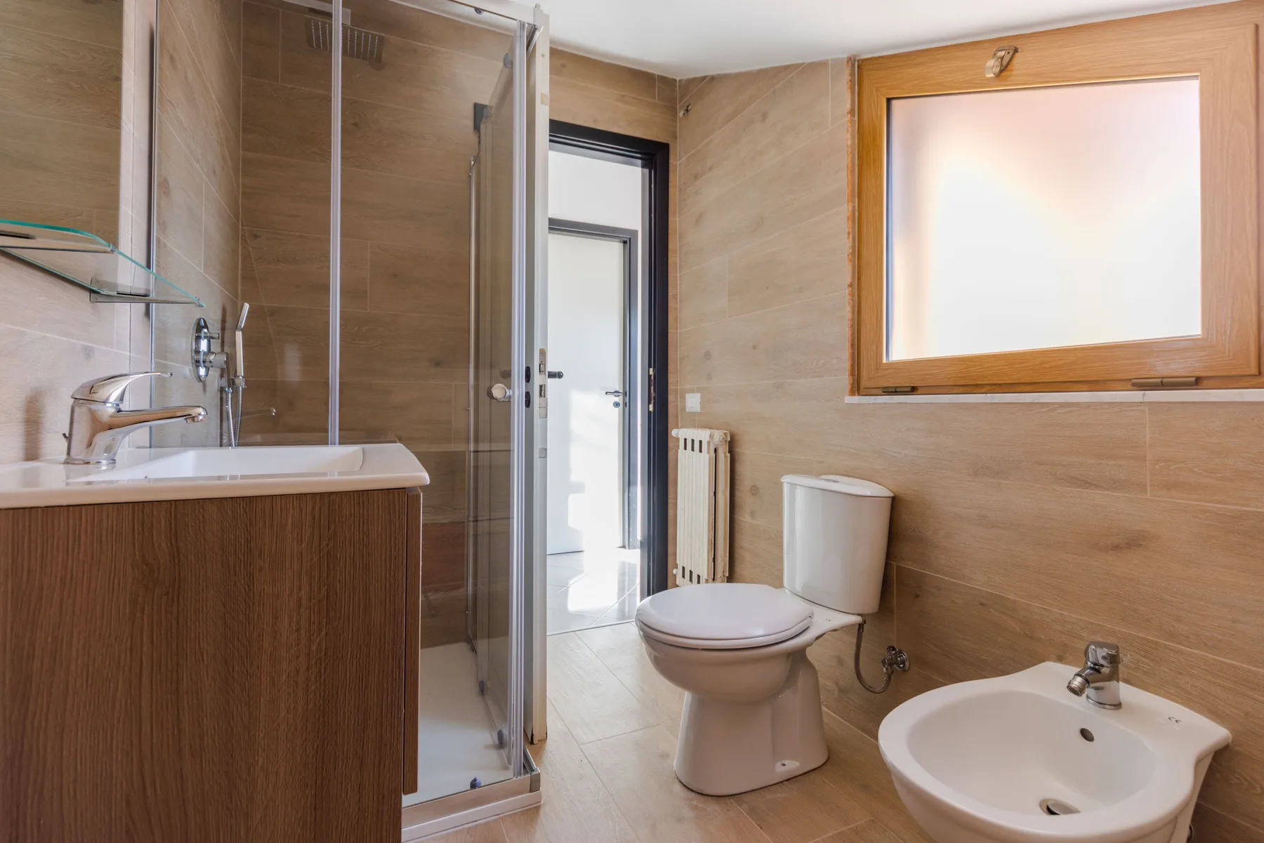 Un baño con ducha de vidrio, mueble de lavabo, inodoro y lavabo.