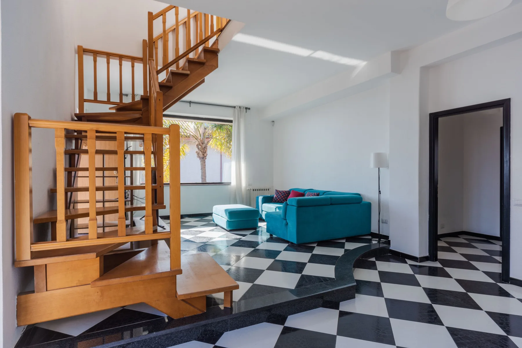 Una sala de estar con asientos turquesa y una escalera de madera.