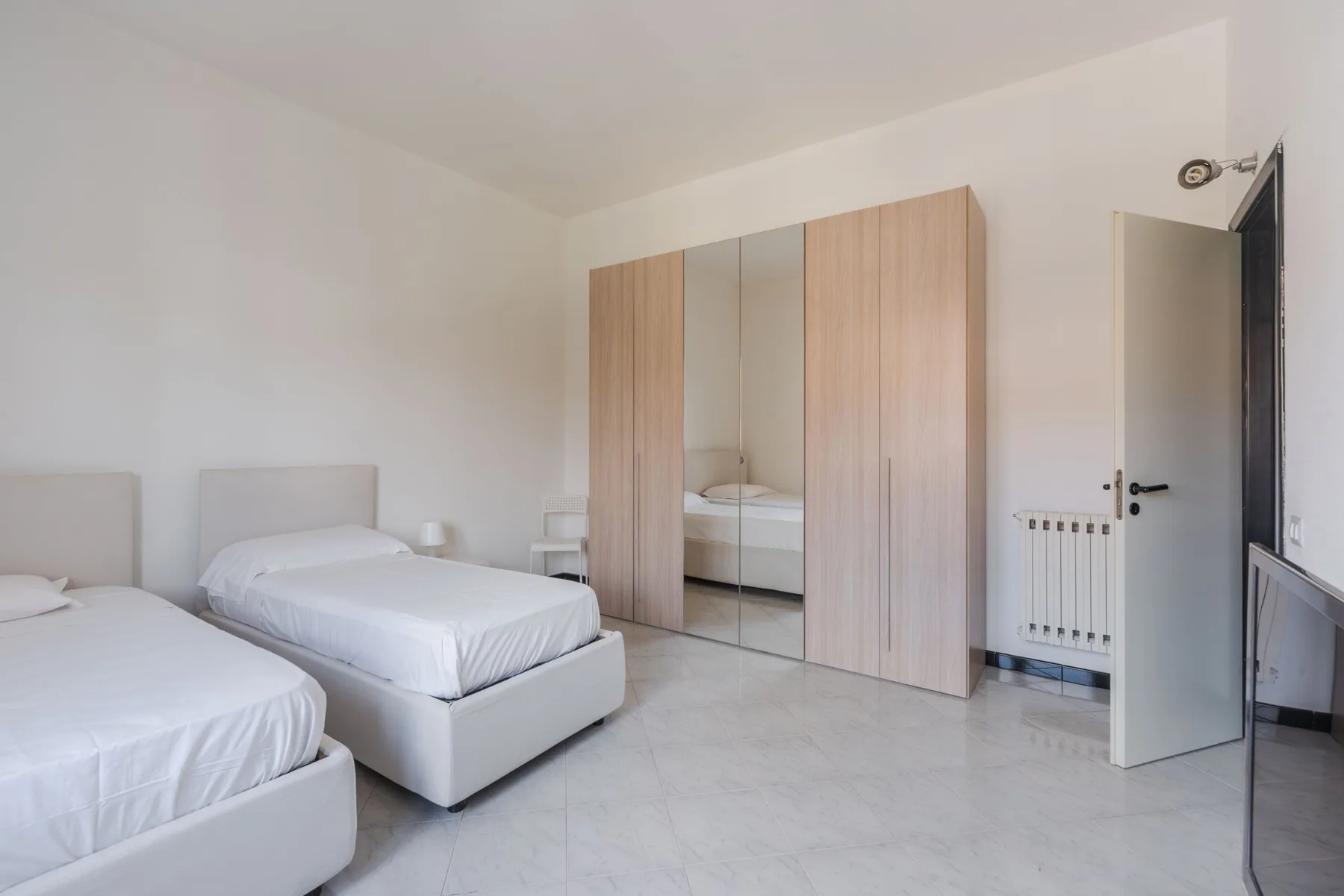Un dormitorio con dos camas y un armario con espejo.