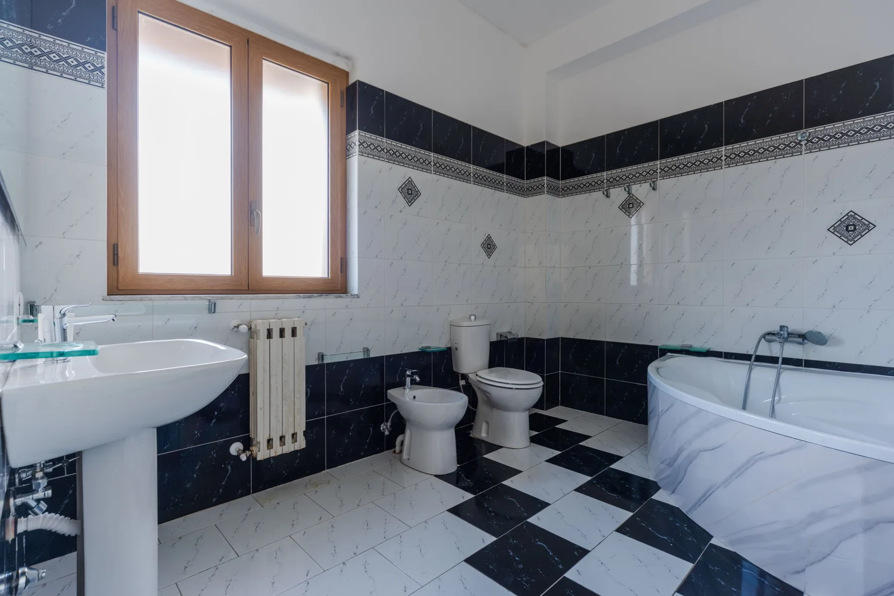 Un baño con azulejos, bañera, lavabo y ventana.