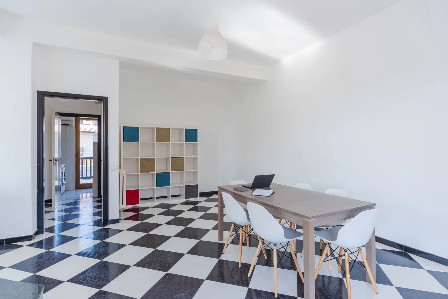 Un comedor luminoso con una mesa, sillas y estanterías abiertas.