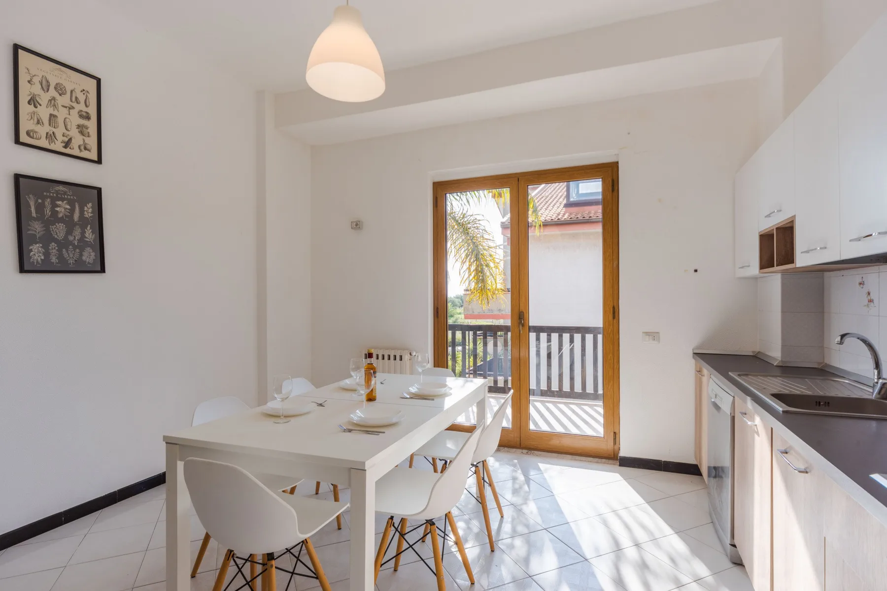 Un comedor luminoso junto a una cocina compacta, con una mesa cerca de las puertas de vidrio.