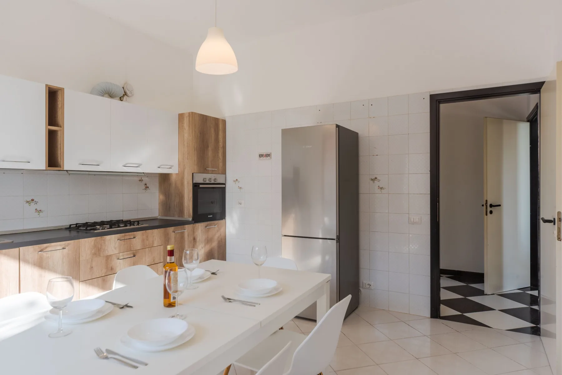 Una cocina luminosa con comedor, armarios blancos y una mesa.