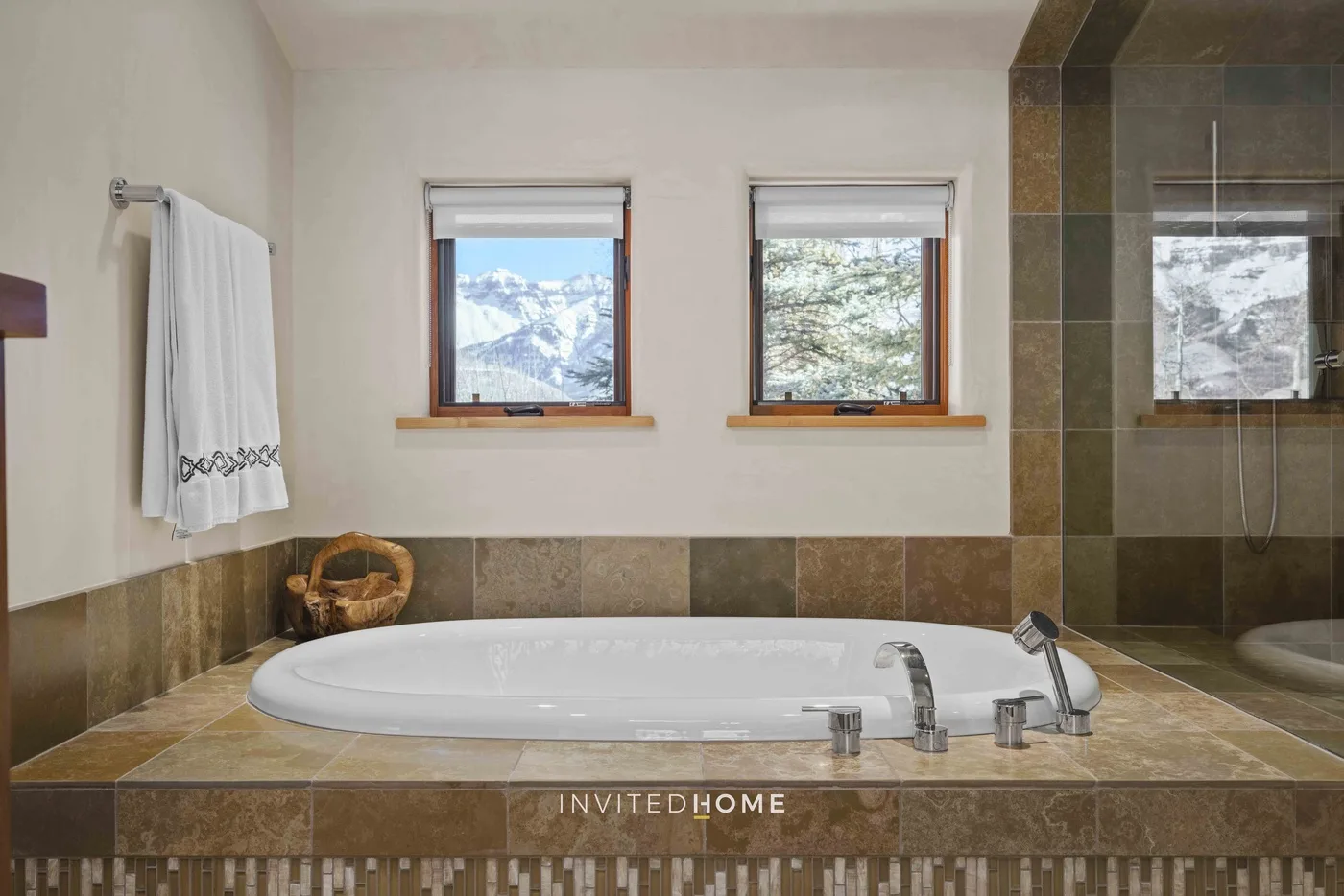 A bathroom with a built-in bathtub beneath two windows.
