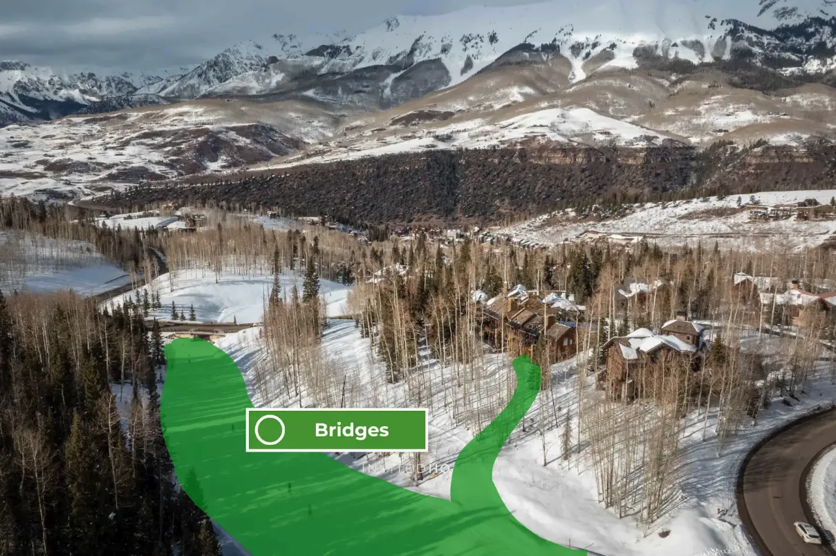 A snowy mountain valley with wooded slopes and a winding road.