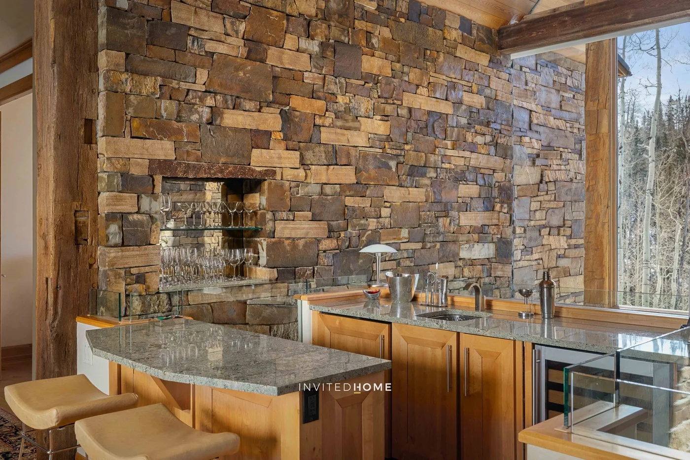 A kitchen with a stone wall, a counter, and wooden cabinetry.