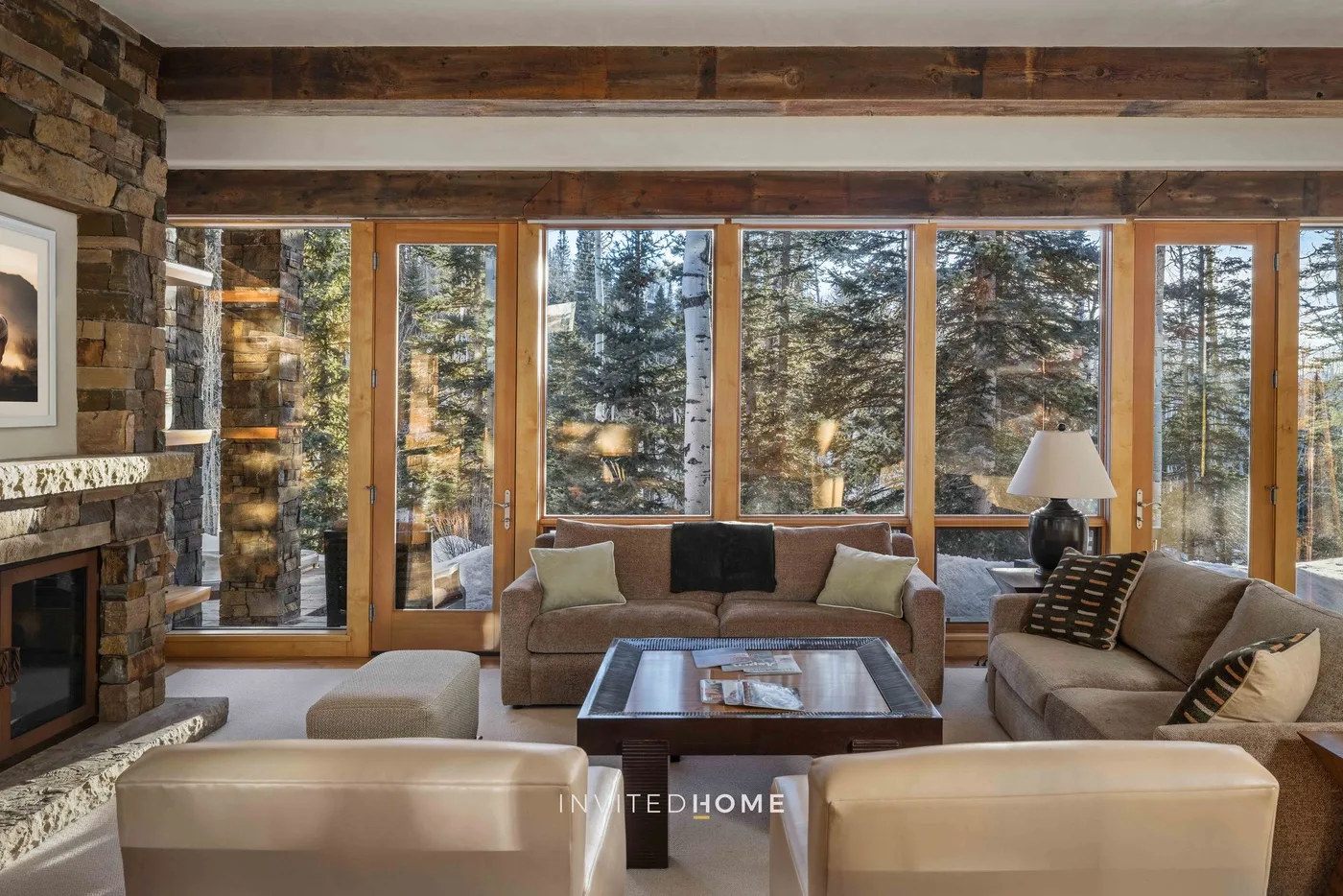 A living room with seating arranged around a coffee table beside large windows.