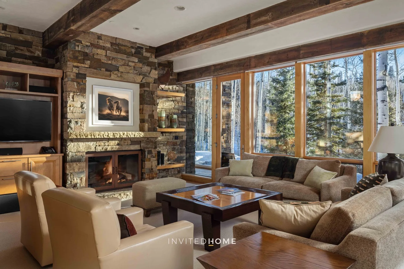A living room with seating arranged around a fireplace and large windows.