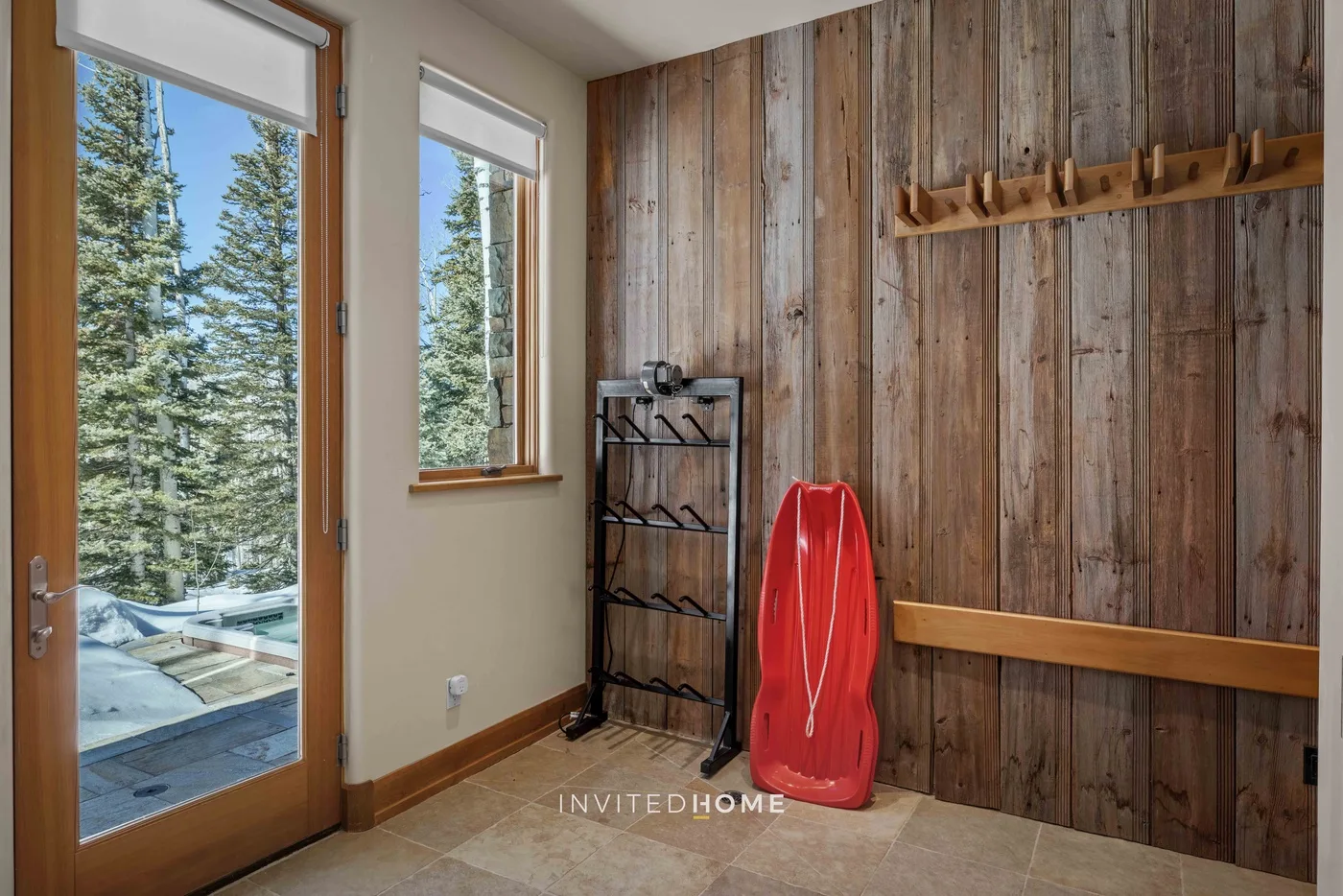 A wood-paneled entryway with tall windows and a red sled.