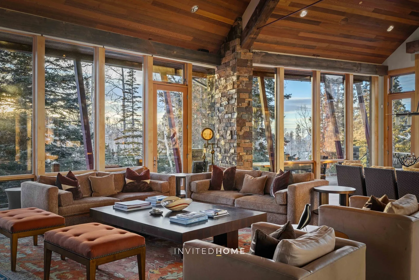 A spacious living room with seating arranged around a low coffee table and large windows.