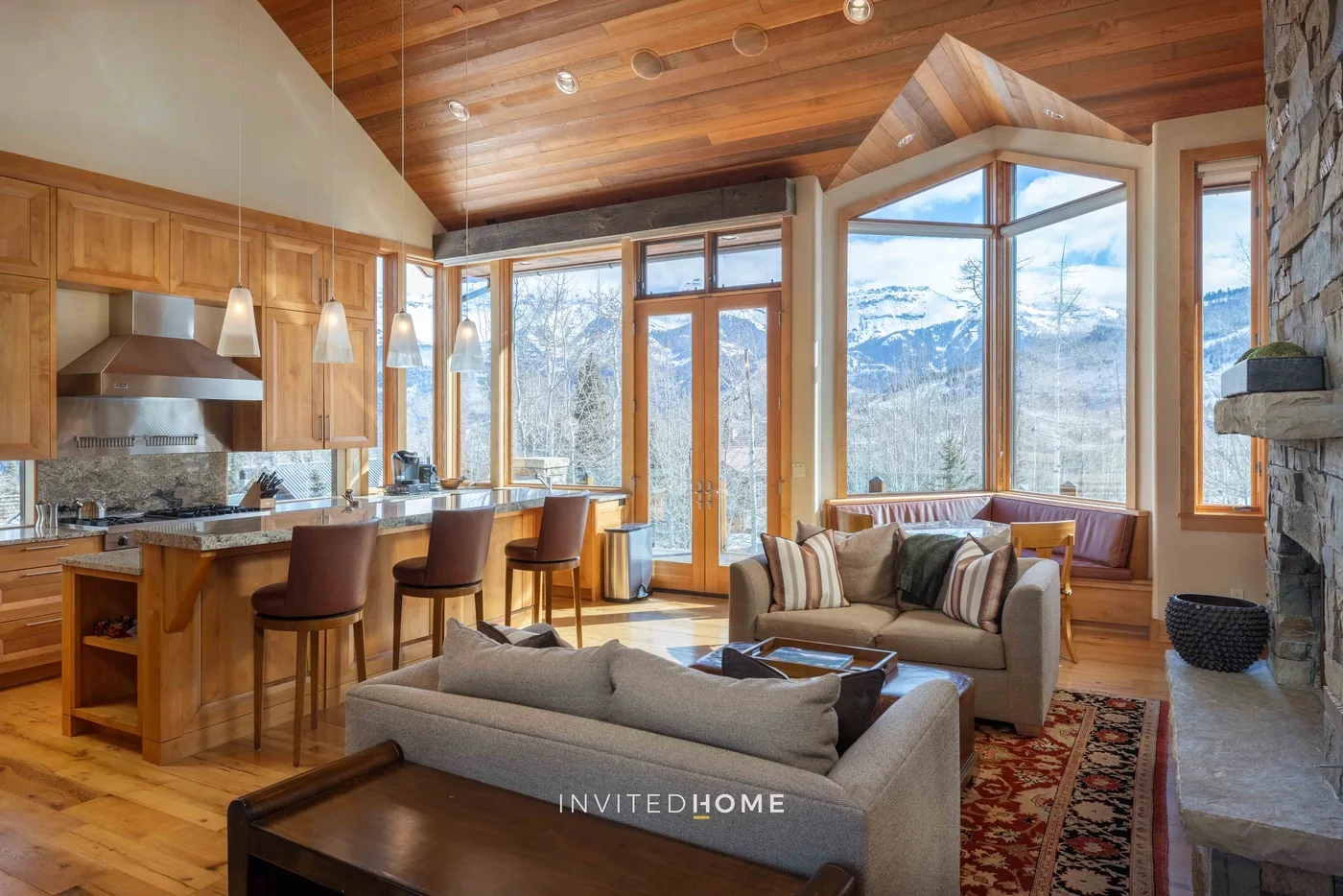 A bright open-plan living room and kitchen with large windows overlooking the mountains.