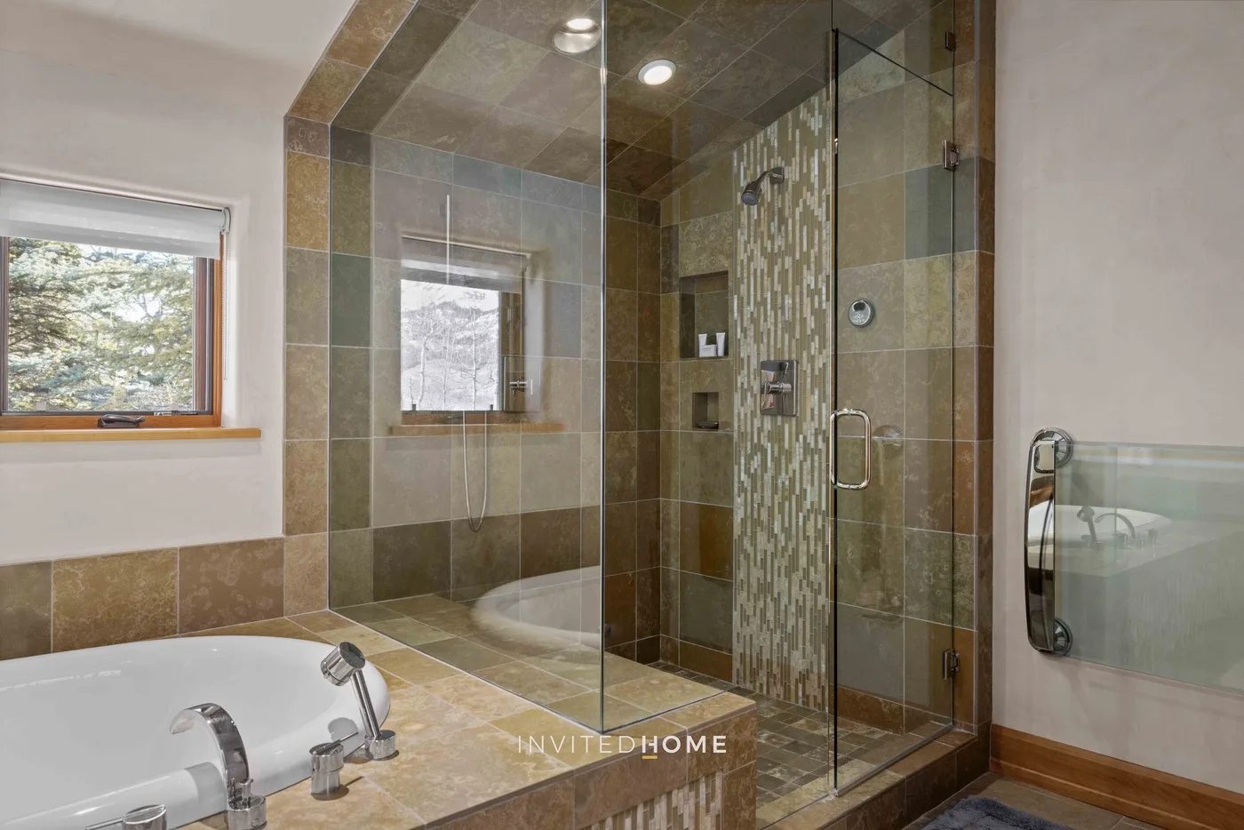 A tiled bathroom with a glass shower and a built-in bathtub.