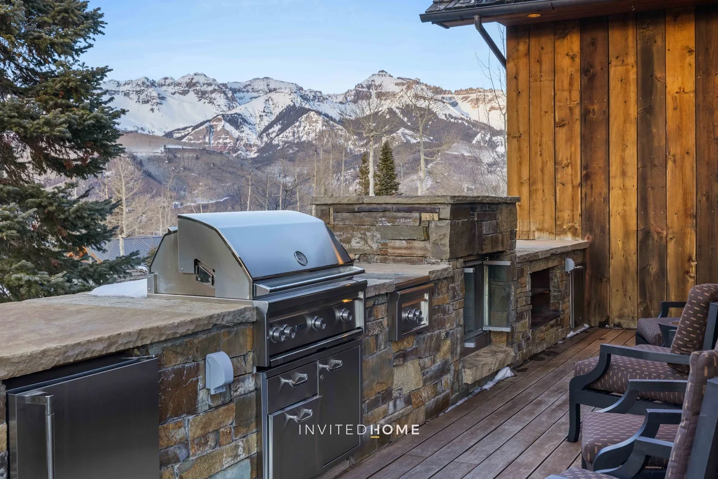 An outdoor cooking area on a wooden deck overlooks a mountain landscape.