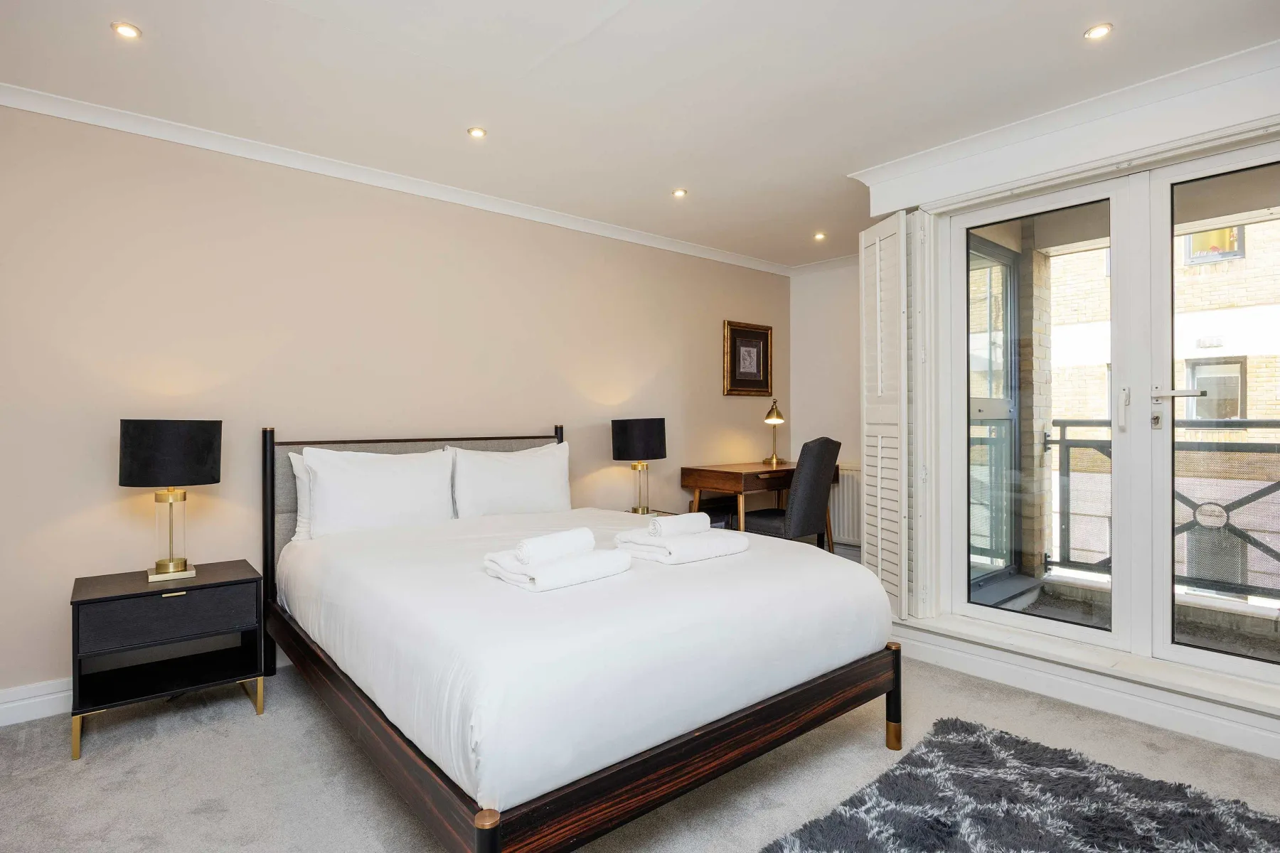 A bedroom with a neatly made bed and glass doors opening onto a balcony.