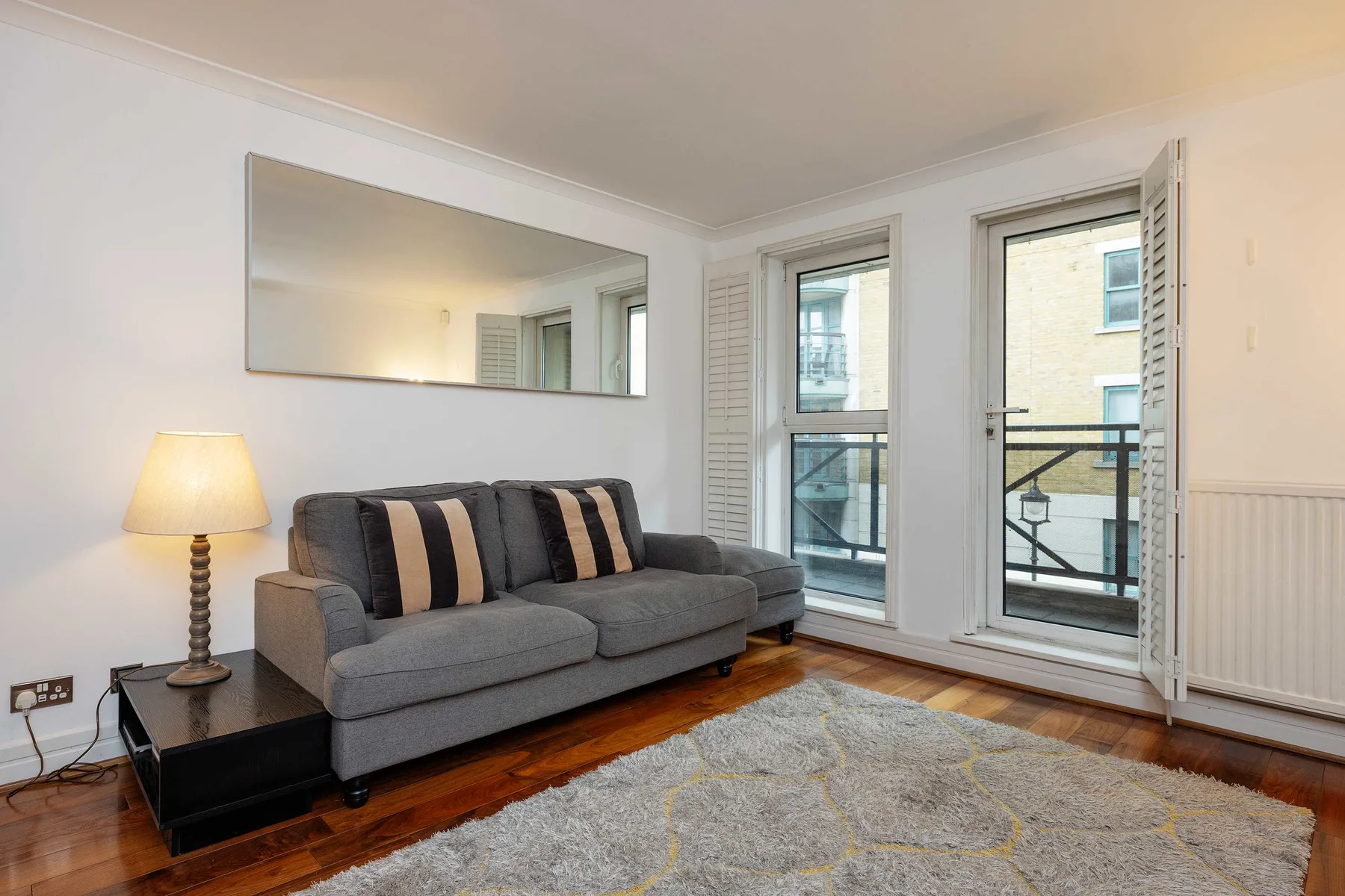 A living room with gray seating, a rug, and tall windows.